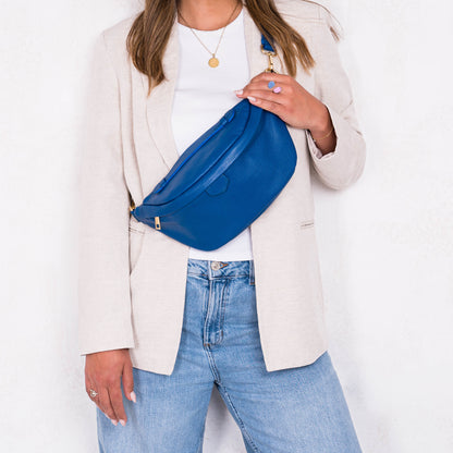 Person wearing a blue waist bag with a plain background