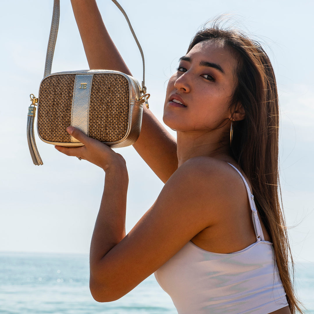 Woman holding a raffia handbag by the ocean