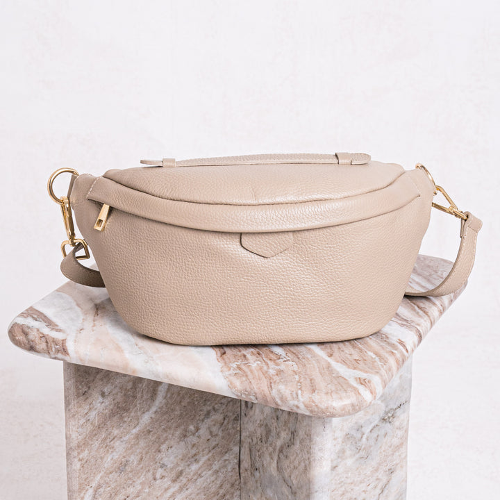 light taupe leather bumbag with gold hardware on marble table 