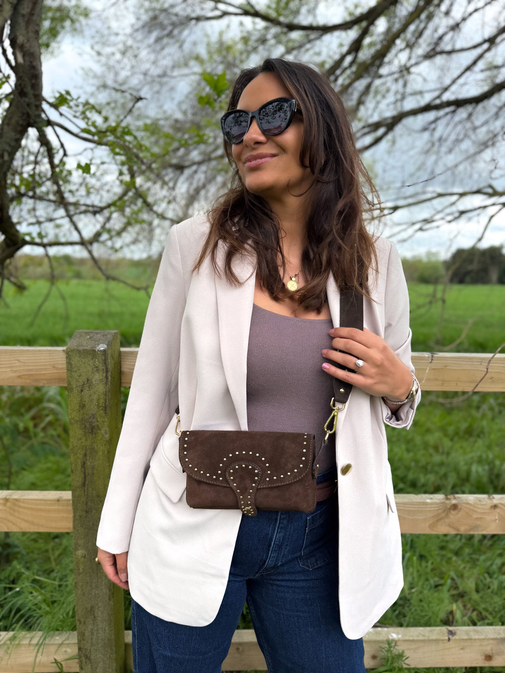 Woman standing outdoors with a brown suede women's bag