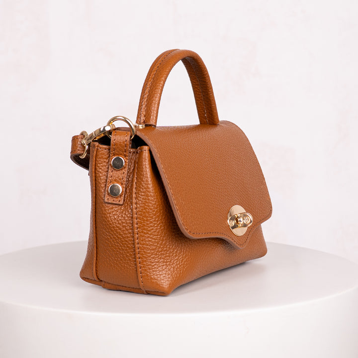 Brown leather handbag with gold accents on a white background